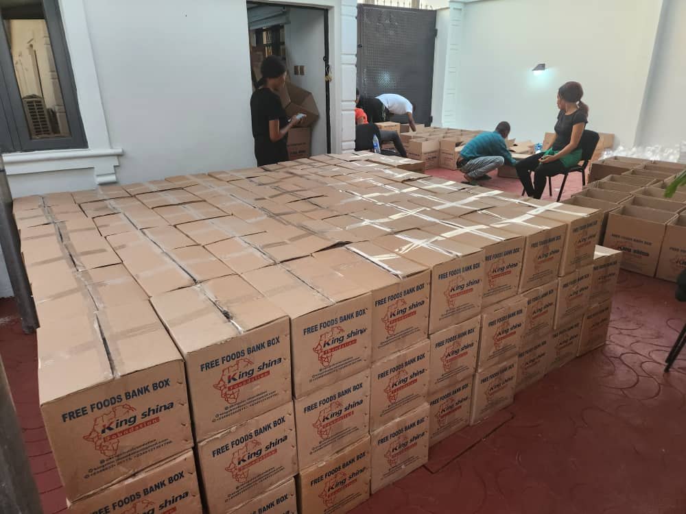 Volunteers packing stacks of Free Foods Bank boxes before distribution