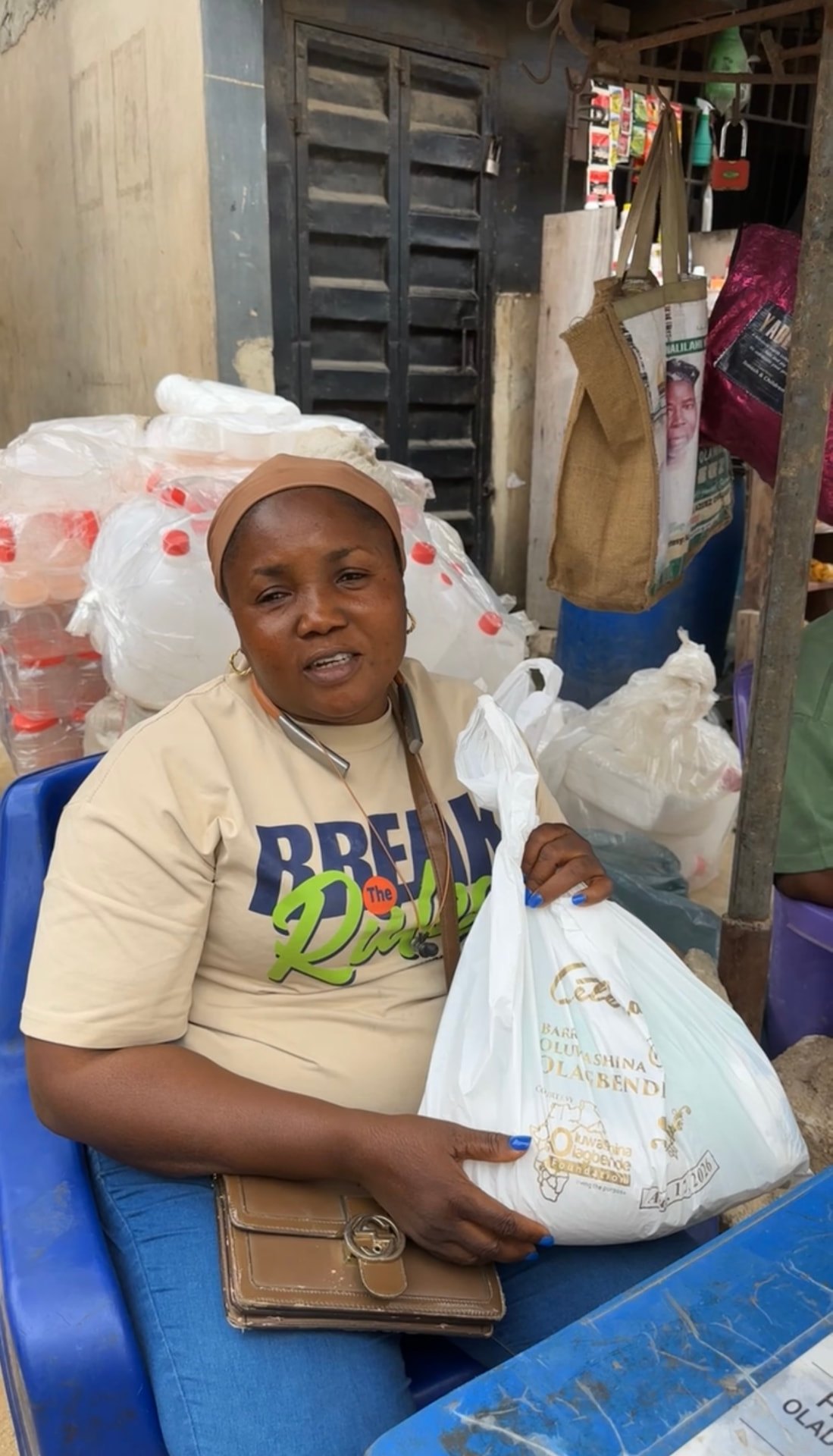 A beneficiary holding a bag of foodstuff from the Foundation at her stall