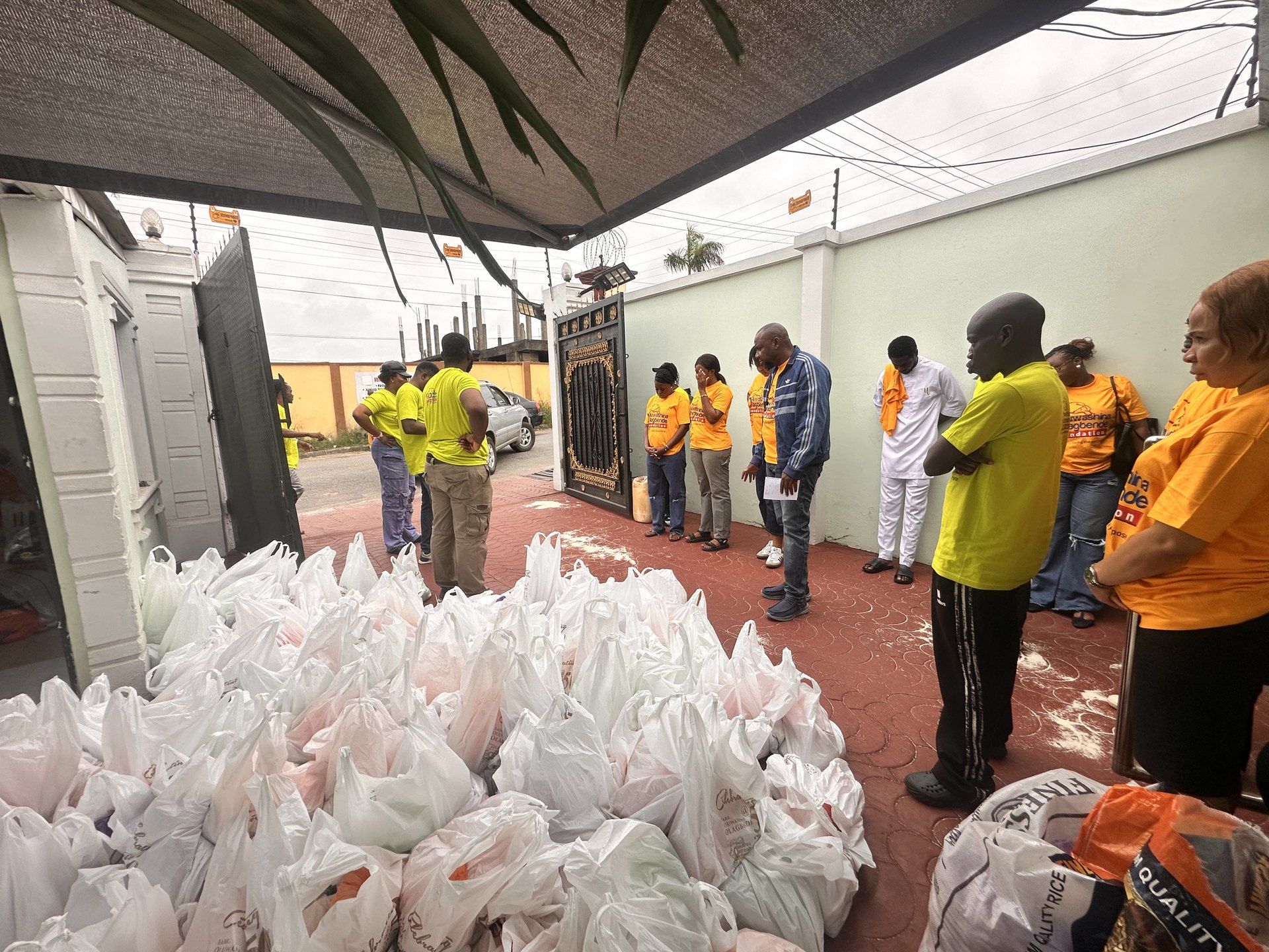 Volunteers in Foundation shirts gathered among packed food bags before distribution